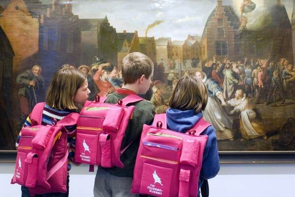 Des enfants aux sacs à dos roses dans le musée