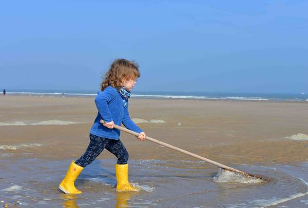 Kind trekt een net door de branding