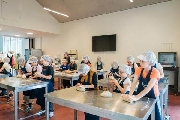 Kinderen kneden deeg met schort en haarnetje