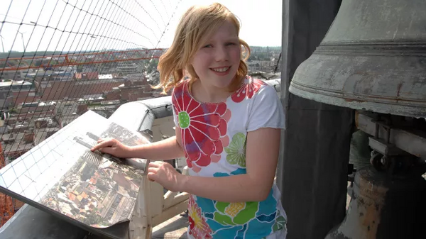 Une fille à côté d'une grande cloche