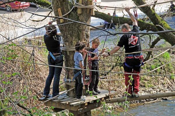 Deelnemers op een hoogteparcours tussen de bomen