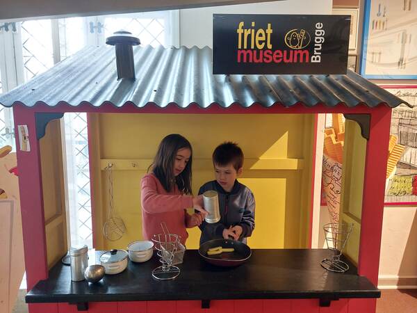 Kinderen achter de toog van een frietkot