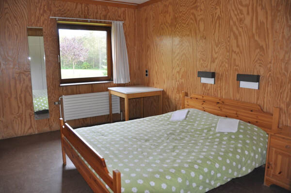 Tweepersoonsbed met houten wandbekleding
