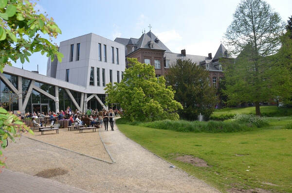 Wit nieuwbouwvolume naast een oude villa
