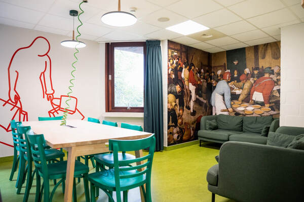Lounge met groene stoelen en muurschildering