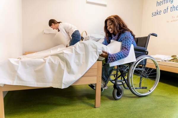 Vrouw in een rolstoel naast een bed