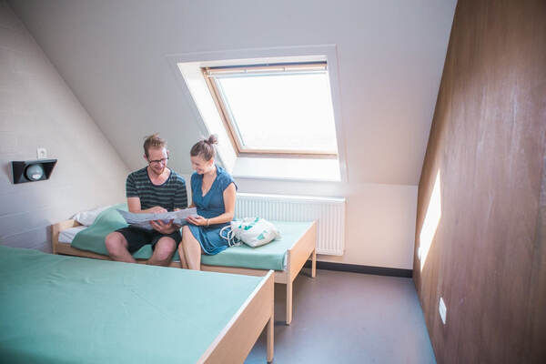 Twee gasten op bed onder een dakraam