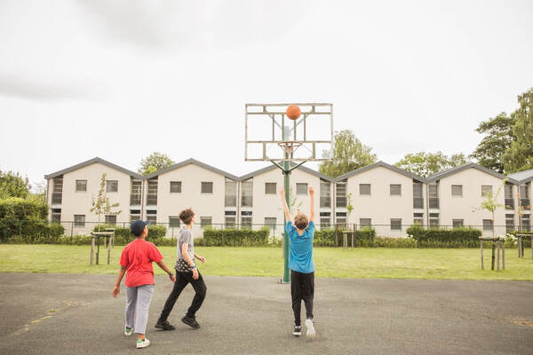 Des enfants jouent au basket sur le terrain extérieur