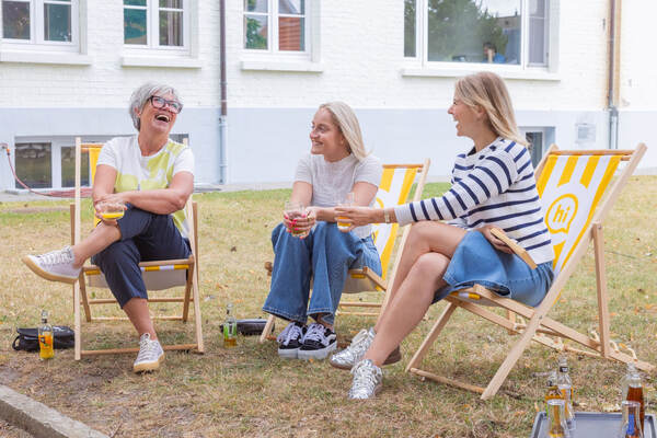 Trois hôtes dans des chaises de plage sur l'herbe