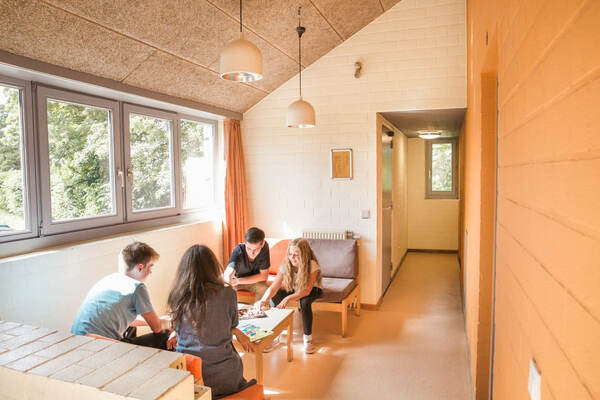 Gasten in de lounge onder een schuin houten plafond