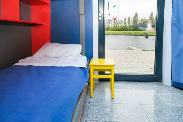 Kamer met een bed en een gele kruk